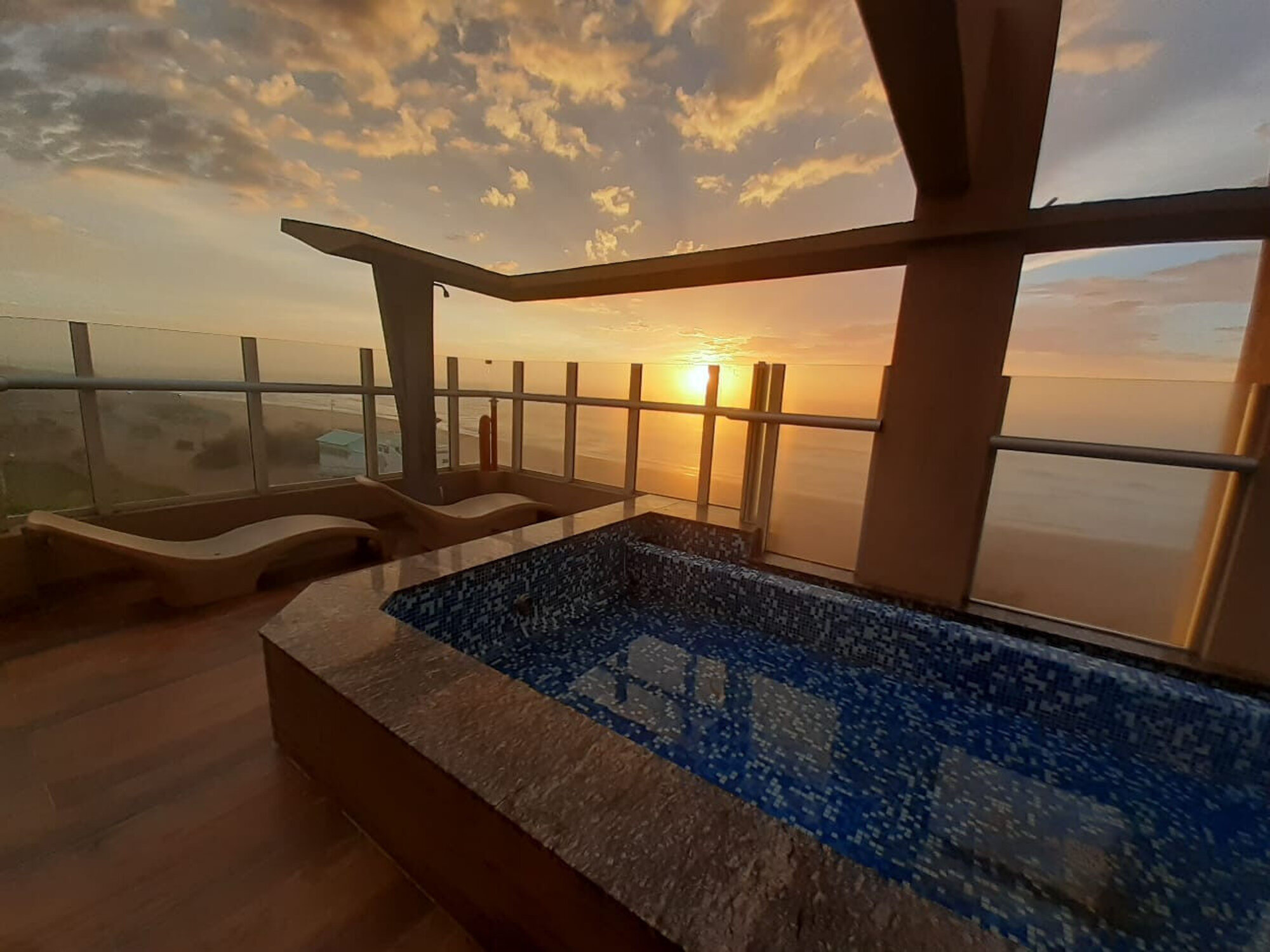 Terraza con piscina y reposeras frente al océano